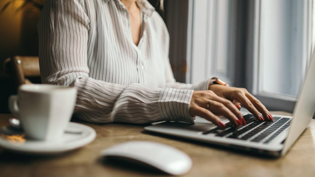 virtual-assistant-using-a-laptop-at-a-home-office-desk-with-a-cup-of-coffee-nearby
