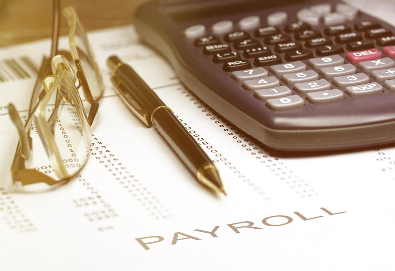 payroll-concept-image-of-a-pen-calculator-and-reading-glasses-on-financial-documents