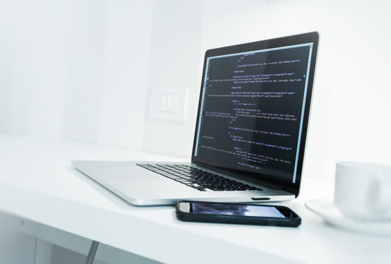 web-application-developer-desk-with-modern-laptop-computer-and-website-source-code-on-display-mobile-work-concept