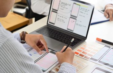 a-laptop-displaying-website-design-software-a-notebook-and-a-pen-for-writing-notes