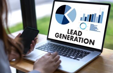 virtual-lead-generation-assistant-working-on-laptop-with-phone-clipboard-mic-and-pen-on-desk-surrounded-by-plants