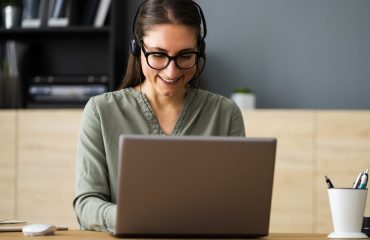 virtual-legal-assistant-working-on-laptop-with-a-smile-holding-a-pen-and-surrounded-by-law-books